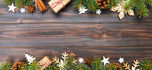 Christmas background with fir tree and gift box on wooden table. Top view banner with copy space...