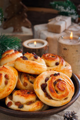 Obraz na płótnie Canvas Buns with raisins in a clay bowl with candles and winter decor, selective focus