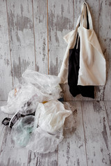 eco-friendly cotton shopping bags hanging vs many plastic bags on a rustic wooden background