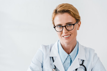 beautiful doctor in glasses looking at camera while smiling in clinic