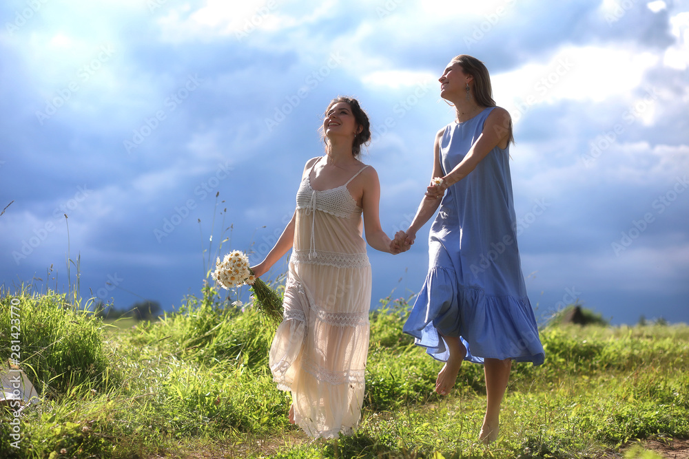 Wall mural young girls are walking in the field