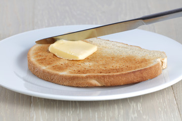 Toast knife and butter on a white plate