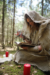 A man in a cassock spends a ritual in a dark forest
