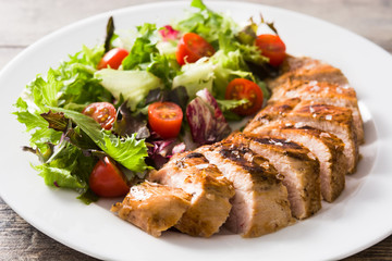 Grilled chicken breast with vegetables on a plate on wooden table