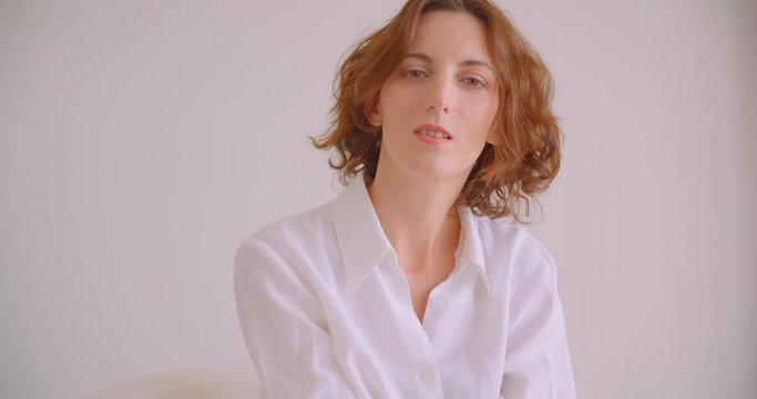 Closeup portrait of redhead caucasian businesswoman looking at camera smiling happily sitting in armchair white office