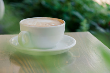 Cup of fresh cappuccino coffee on the table in summer cafe