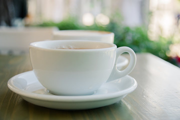 Cup of fresh cappuccino coffee on the table in summer cafe