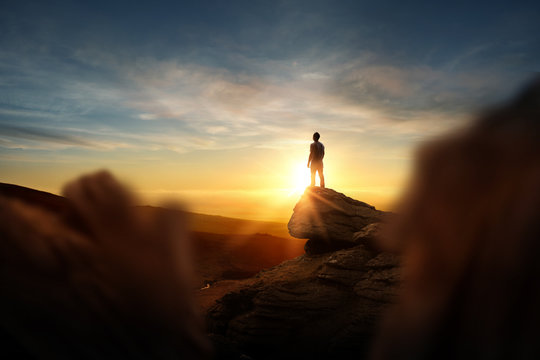 Leadership And Goals. A man standning on top of a mountain watching the sun set. Conceptual photo composite.