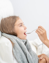 Sick little girl take medication pouring in a spoon