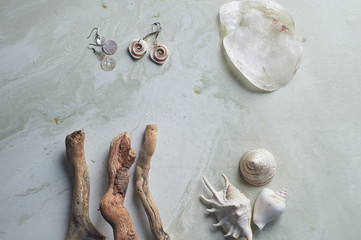 Sea collection on grey marble background.Seashell and mother-of-pearl earrings. Summer jewelry.
