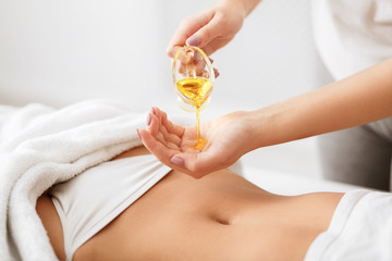 Obraz na płótnie Canvas Masseur pouring oil on hand, preparing for massage
