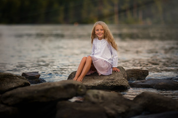 Portrait of a cute girl on the lake in the sunset on a summer evening.