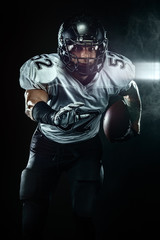 Fototapeta na wymiar American football player, sportsman in helmet on black background with smoke. Sport and motivation wallpaper.