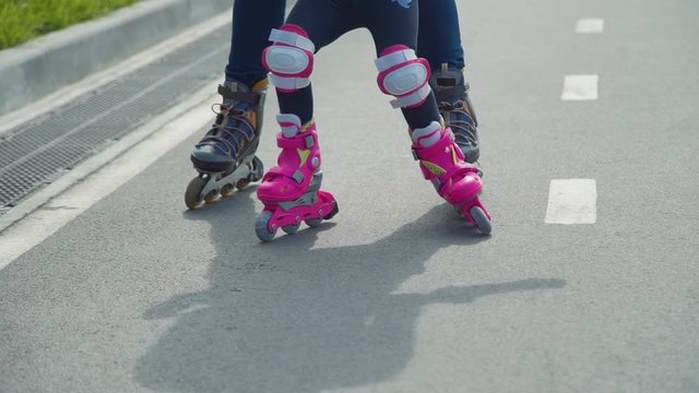 Close Up of Mother Teaching her Daughter Rollerblading. Little Girl with Mother Roller Skating Outdoors. Active Family Lifestyle Concept