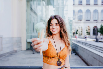 Beautiful young caucasian woman eating mint ice cream at the city street on a sunny day. Happy face smiling. Urban and summer lifestyle