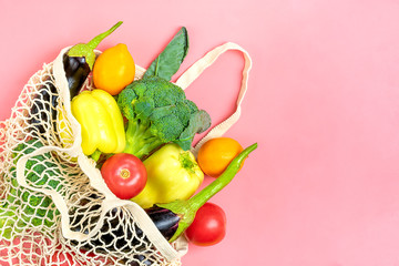 Eco friendly mesh shop bag with organic green vegetables on pink background. Flat lay, top view. Zero waste, plastic free concept. Healthy clean eating diet and detox concept