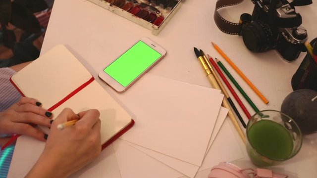 student painting from smartphone on table with art objects watercolor brush studio home loft 5g green screen chroma key social technology media study design tutorial illustrator work freelance