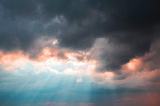 Heavenly Dramatic Landscape Background. Bad Weather, Thunderstorm, Black Clouds, Storm. The Concept Of The Struggle Of Light And Darkness. The Shining Of The Sun's Rays In The Blue Sky Through, Sunset