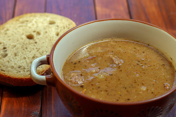 Traditional Slovakian beef goulash with peppers and potatoes on wood table. With piece of bread.