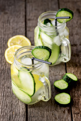 Glass Jar of Fresh Cold Water with Lemon and Cucumber Infused Water Healthy Detox Water with Lemon and Cucumber Wooden Background Horizontal Copy Space