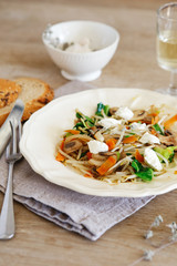 Mixed vegetable stir fry with mushrooms and cottage cream cheese. Tender mushroom stir fry served in a white plate with white wine and bread on the wooden table. Vegan food