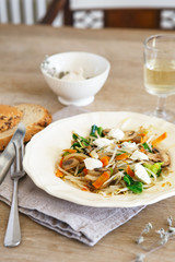 Mixed vegetable stir fry with mushrooms and cottage cream cheese. Tender mushroom stir fry served in a white plate with white wine and bread on the wooden table. Vegan food