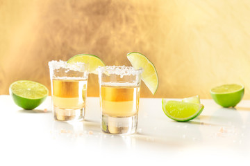 Golden tequila shots with salt, lime slices, and copy space