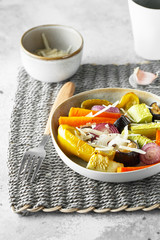 Mixed vegetable stir fry with parmesan cheese. Roasted vegetables mix on the plate with cutlery on the wicker serving mat, food above. Tender seasonal vegetables stir fry. Vegan food