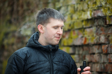 Vape man. Young caucasian white guy in black jacket smoking and letting off steam from an...