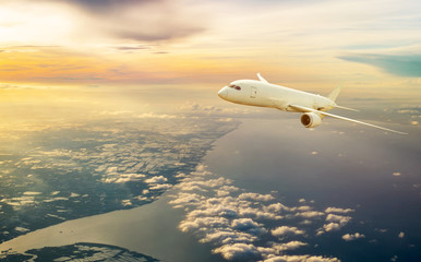 Commercial airplane jetliner flying above clouds in beautiful sunrise light , Ariel view from an aircraft flying over the Ocean and Andaman , Travel and business concept.