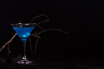 Halloween blue cocktail with artificial eyeballs in a liquid on a black background