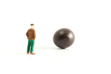 Miniature people standing around a mysterious object (bingo ball)