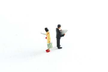 Miniature People Looking at Media/Newspaper/Phone Standing on a White Isolated Background