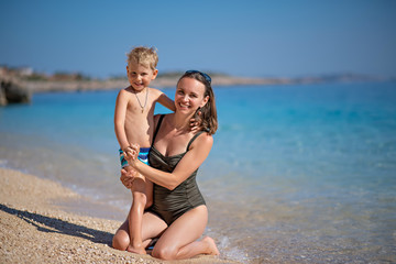 Fototapeta premium mother with the son sit on the seashore with transparent goduby water, active holiday