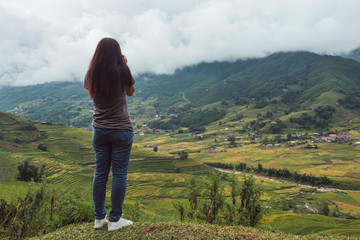 Fototapeta premium Young asian woman take a photo on top of rice fields