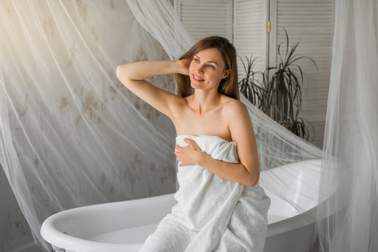 beautiful young woman in a towel sitting on a bath