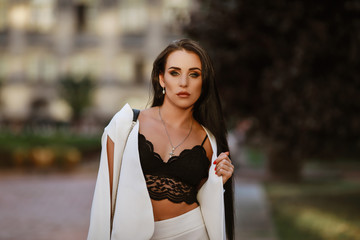 Fototapeta premium beautiful brunette woman with long hair in a white suit and lace top