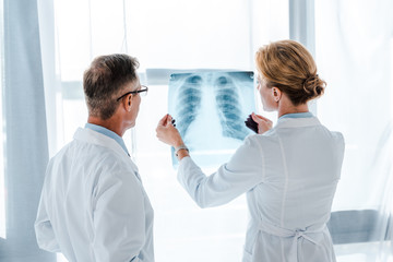 doctor in glasses looking at x-ray in hands of coworker