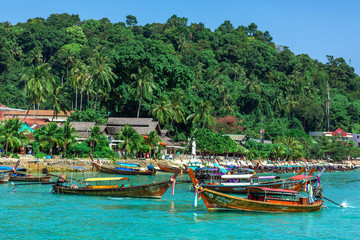 Traditional Thai fishing boats wrapped with colored ribbons. Against the backdrop of a tropical island