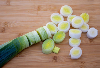 Organic fresh cutted leeks on the wooden cutting board. Leek cut by means rings on a chopping board. Slices of the fresh green leek. Cooking ingredients.
