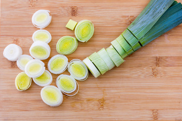 Organic fresh cutted leeks on the wooden cutting board. Leek cut by means rings on a chopping board. Slices of the fresh green leek. Cooking ingredients.