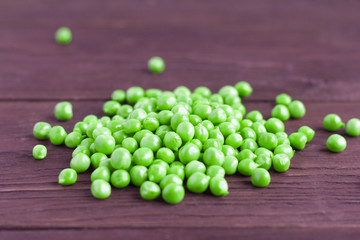 young green peas scattered on a wooden background