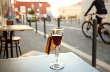 City cafe with drink on table of outdoor cafe. Liquor at evening time with street life background