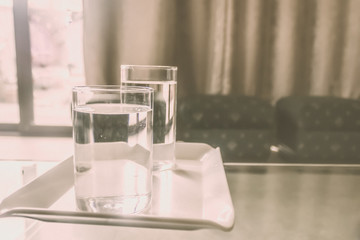 2 Glasses of Drinking Water on table. Morning Sunlight coming from window. Two glasses of pure warm water after wake up in morning. Good morning habit. Vintage tone. Copy space room for text on left.