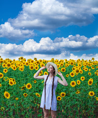 Fototapeta premium Portrait of a young beautiful girl in a field of sunflowers