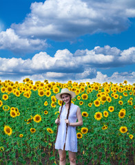 Fototapeta premium Portrait of a young beautiful girl in a field of sunflowers