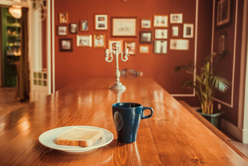 Breakfast inside dinning room of old house. Cheese sandwich and hot coffee for morning table