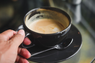 closeup woman drinking modern hot black coffee the cappuccino on dark background with coffee bubble foam pattern and texture in black cup looking and feel so delicious on glasses table in coffee shop.
