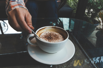closeup woman drinking modern hot black coffee the cappuccino on dark background with coffee bubble foam pattern and texture in black cup looking and feel so delicious on glasses table in coffee shop.