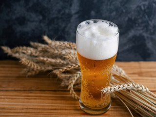 Misted glass of light beer on a wooden table and wheat
